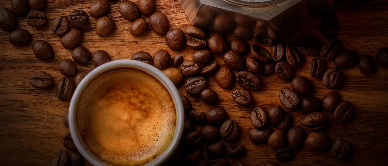 Une tasse d'expresso, des grains et du café fraîchement moulu, vus de dessus.